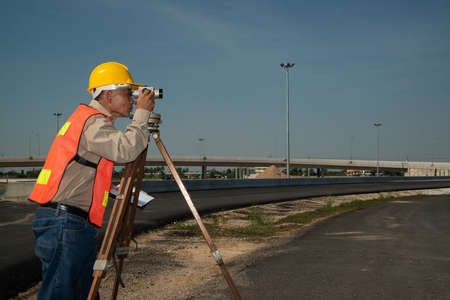 Engineer or surveyor working with theodolite equipment at road construction site.の写真素材