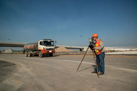 Engineer or surveyor working with theodolite equipment at road construction site.の写真素材