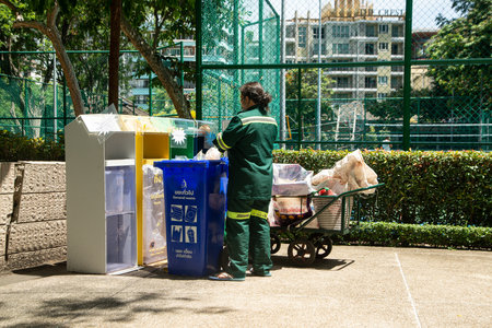 BANGKOK ,THAILAND - JUNE 6 , 2022 : Unidentified female worker is sorting waste from classified waste bins at Benchasiri public park. Which is a daily work.のeditorial素材