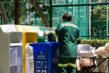 BANGKOK ,THAILAND - JUNE 9 , 2022 : Unidentified female worker is sorting waste from classified waste bins at Benchasiri public park. Which is a daily work.のeditorial素材