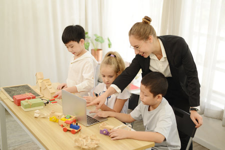 Teacher teaching her young students drawing toys or wood model on the laptop.