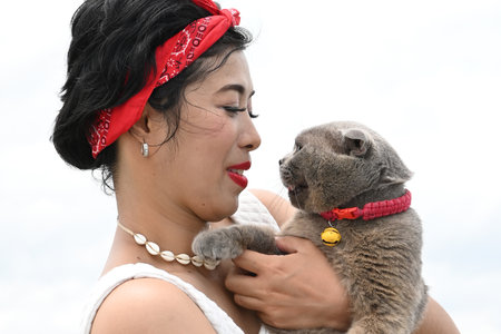 Pretty Asian female hold her the orange eyes of a Scottish Fold cat on white background.の写真素材