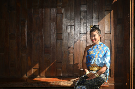 Beautiful Thai woman in National costumes pose sitting in a Thai-style house.の写真素材