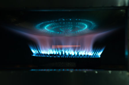 Natural gas blue fire flame on kitchen burner gas stove on dark background.の写真素材