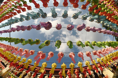Colorful paper lanterns hanging in the sky at a Buddhist templeの写真素材