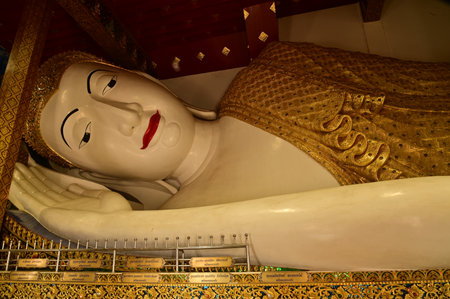 The Reclining white statue Phra Chaeo Nip Phran Buddha is enshrined in a teakwood chapel at Wat Den Sali Si Mueang Kaen temple or Wat Ban Den. Located at Chiang Mai in Thailand.の写真素材