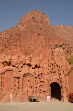 Buddha statue sculpture on the cliff face of the temple in front of the entrance gate at the...