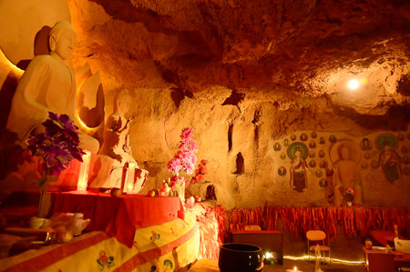 Buddha statue sculpture in a cave of the temple in front of the entrance gate at the Tianshan Grand Canyon, or Kesileya Grand Canyon, is a stunning natural feature in Xinjiang.の写真素材