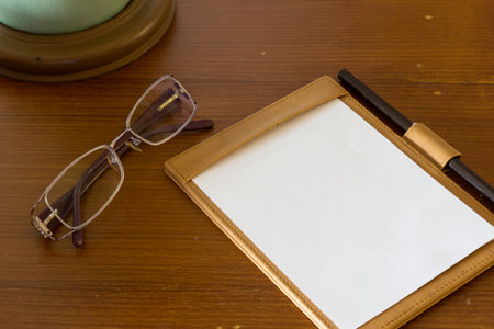 background, texture of notebook paper with pencil and spectacles on wood tableの写真素材