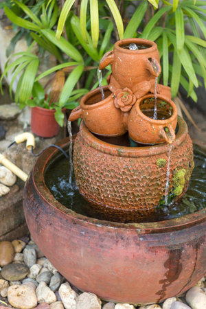 the water is drop from clay jug in nature gardenの写真素材