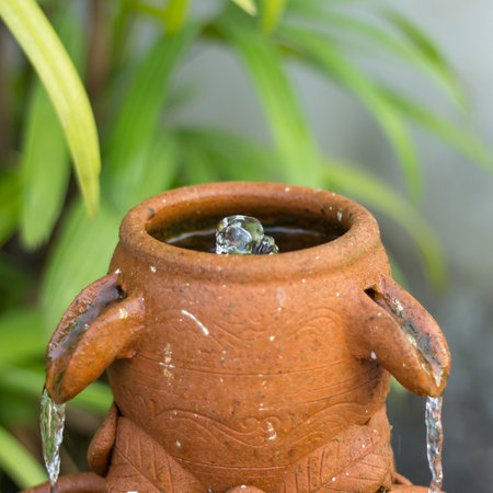the water is drop from clay jug in nature gardenの写真素材