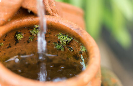 the water is drop from clay jug in nature gardenの写真素材