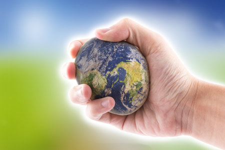 hand is holding to the stone world on blue sky backgroundの写真素材