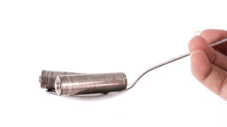 the isolated of old AA battery in spoon is energy consumption concept on white background