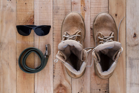 Still life art photography concept with boots, belt and sunglasses on wood backgroundの写真素材