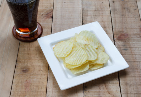 Potato chips and soft drink in glass on wood background, Selection focus