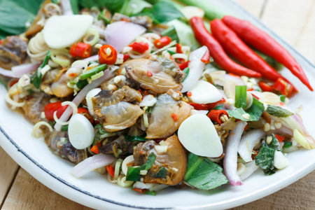 spicy cockle salad on wooden background, selection focus