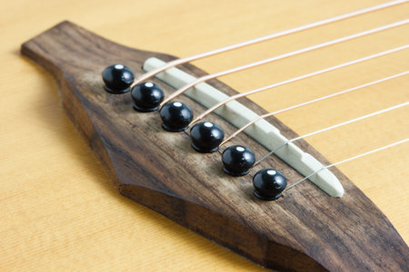 Still life photo by acoustic guitar bridge, pins and saddle