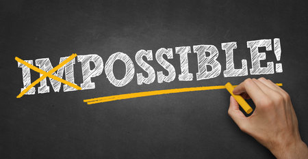 hand writes chalk text on blackboard - make the impossible possible