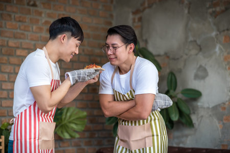 Young asian men couple friend cooking pizza food in the kitchen at home for holiday festival celebration.. LGBT, Gay, Lifestyle and love relationship conceptの写真素材