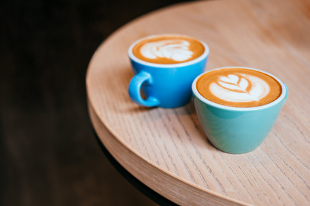 Two blue cups of cappuccino with beautiful latte art on the table.の写真素材