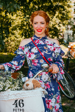 Kiev, Ukraine - May 12, 2018: Girl in floral print vintage dress participating in bicycle tweed run Retro cruise on May 12, 2018 in Kiev, Ukraine.のeditorial素材