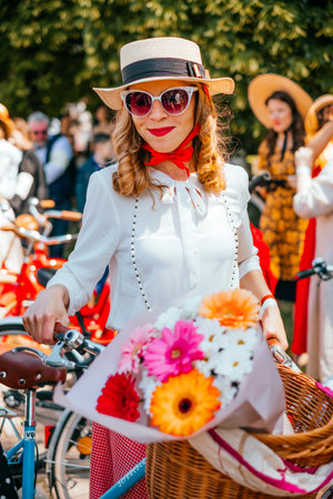 Kiev, Ukraine - May 12, 2018: Girl in white bow tie blouse, straw hat and red lipstic participating in bicycle tweed run Retro cruise on May 12, 2018 in Kiev, Ukraine.のeditorial素材