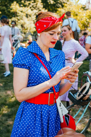 Kiev, Ukraine - May 12, 2018: Girl in blue dotted vintage dress with red details and headband participating in bicycle tweed run Retro cruise on May 12, 2018 in Kiev, Ukraine.のeditorial素材