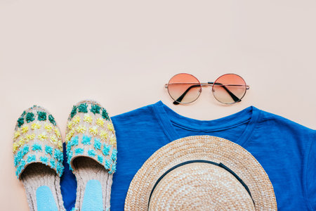 Summer fashion flatlay with gradient round sunglasses, straw hat, espadrille sandals and t-shirt on the beige background. Perfect beach set for holidays on the sea. Marina style.の写真素材