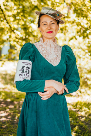 Kiev, Ukraine - May 12, 2018: Girl in teal color vintage dress with lace details, straw hat with peacock feather participating in bicycle tweed run Retro cruise on May 12, 2018 in Kiev, Ukraine.のeditorial素材