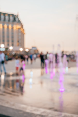 Blurred background with group of kids playing in the fountain on the hot summer evening.の写真素材