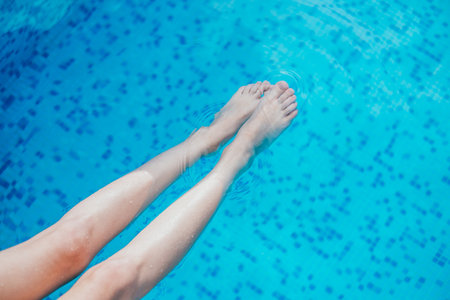 Beautiful female legs in the blue swimming pool water.