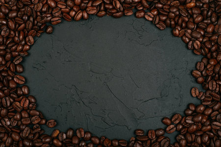 Roasted brown coffee beans on the black concrete stone background. Flatlay style, messy pattern.の写真素材