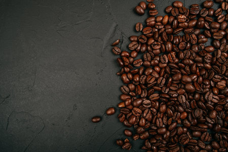 Roasted brown coffee beans on the black concrete stone background. Flatlay style, messy pattern.の写真素材