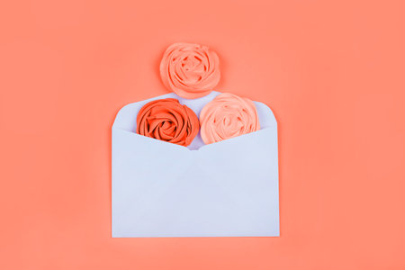 Beauty flatlay for with colorful living coral flower shaped meringue in the white envelope.の写真素材