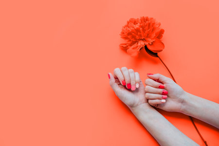 Creative bright trendy summer manicure with nails of different color. Female hands with art nail design on pink background and fuchsia peony flower.の写真素材