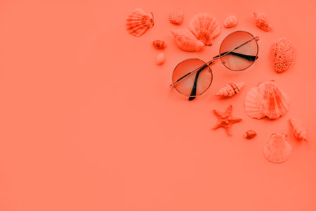 Coral summer fashion flatlay with gradient round sunglasses. Decorated with sea shells and starfish. Perfect beach set for holidays on the sea. Marina style.の写真素材