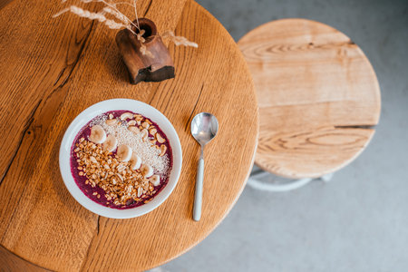Beautiful blueberry banana smoothie bowl with a spoon on wooden table. Healthy breakfast concept.の写真素材