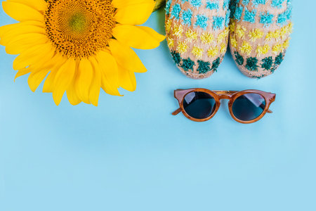 Fashion flatlay with sunglasses, espaddrille sandals and bright big yellow sunflower on blue background. Flatlay style.の写真素材