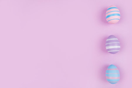 Three dyed on blue, pink and violet Easter eggs isolated on purple background. Easter theme flatlay.の写真素材