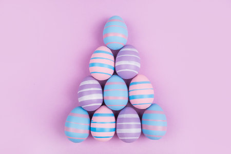Pyramid of dyed on blue, pink and violet Easter eggs isolated on purple background. Easter theme flatlay.の写真素材