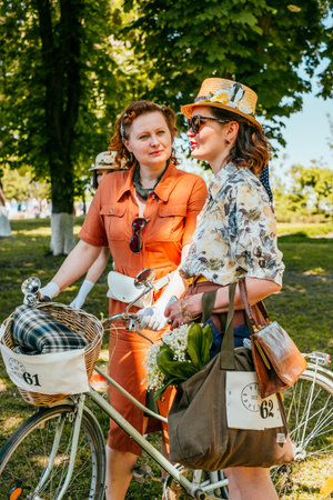 Kiev, Ukraine - May 19, 2019: Two ladies in vintage dresses participating in bicycle tweed run Retro cruise in Kiev, Ukraine.のeditorial素材