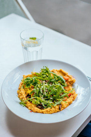 Bowl of carrot vegan hummus with chickpea, caramelized carrot, mushrooms, garlic, paprika, tahena,...