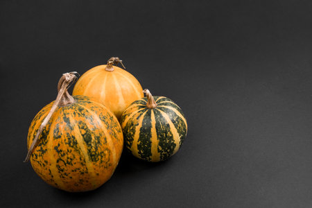 Flatlay with three Halloween pumpkins on black background.
