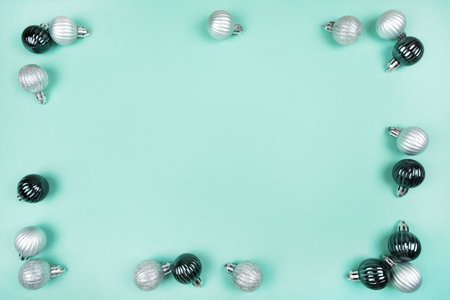 Frame made of silver and pine green Christmas baubles isolated on mint green background. Christmas...