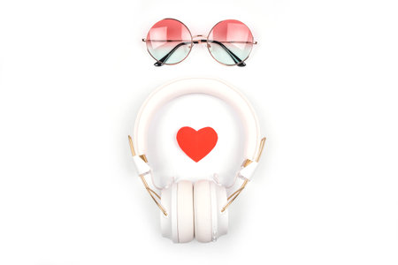 Flatlay with white wireless headphones, gradient round sunglasses and red heart isolated on white background.の写真素材