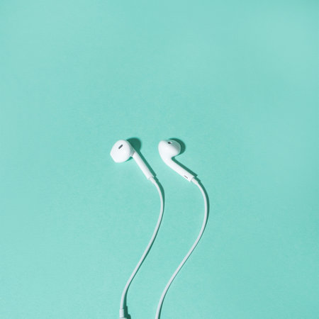 Flatlay with white earphones isolated on turquoise background.の写真素材