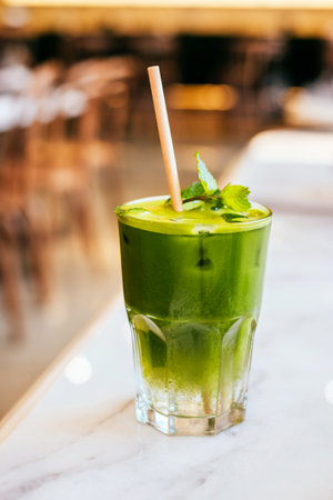 Glass of matcha green tea lemonade with paper straw on marble table with blurred background.の写真素材