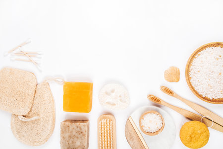 Flatlay with wooden brush, bamboo toothbrushes, bar of soap, konjac and loofahs sponges, cotton earbuds and sea shells isolated on white background. Zero waste concept.の写真素材