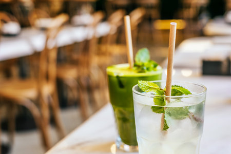 Two glasses of matcha green tea and classic lemonades with paper straw on marble table with blurred background.の写真素材